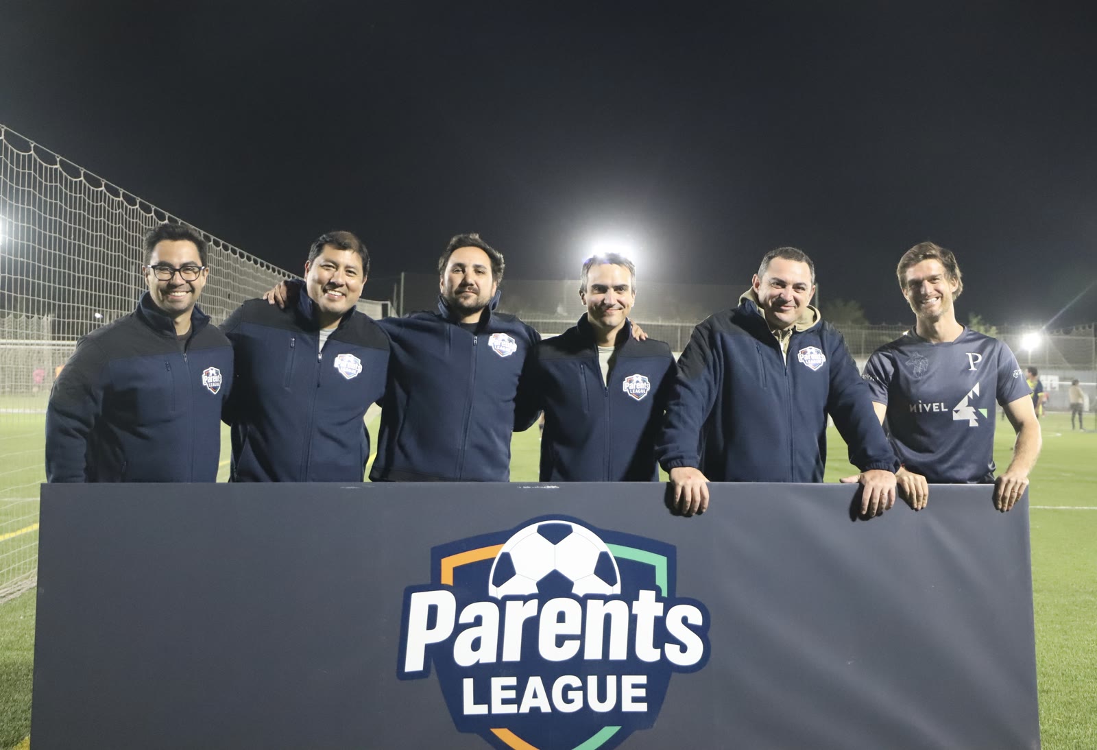 Socios de Parents League con el banner oficial en la cancha